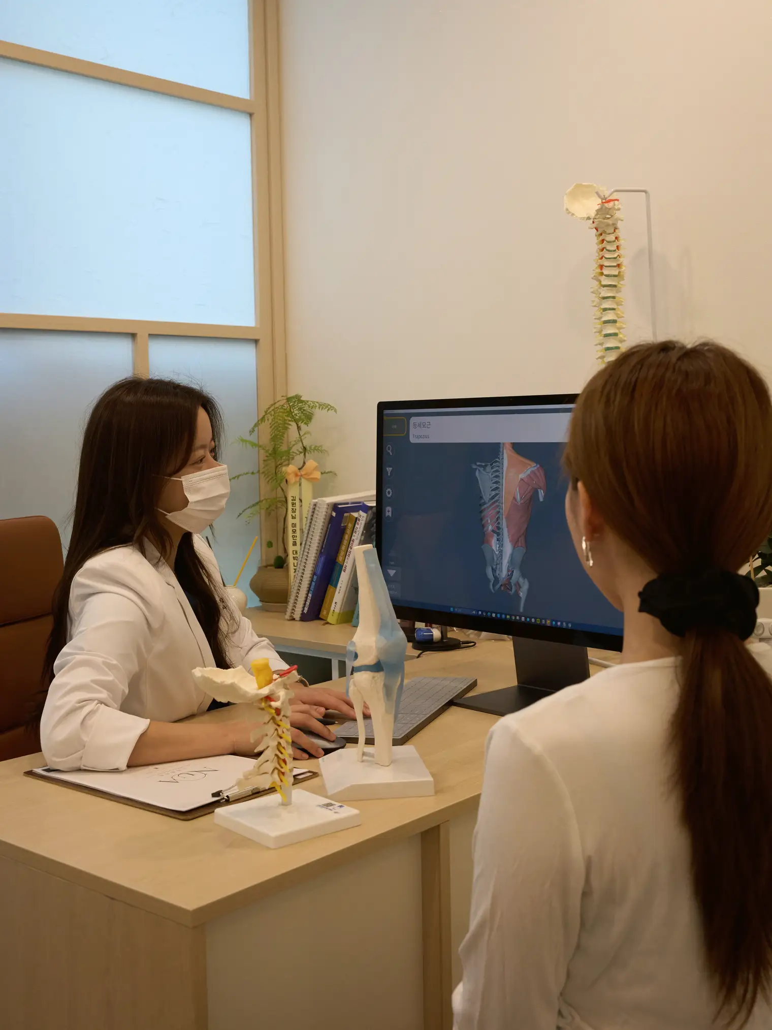 진료실 책상에서 모니터를 보며 상담하는 김정현 원장과 환자